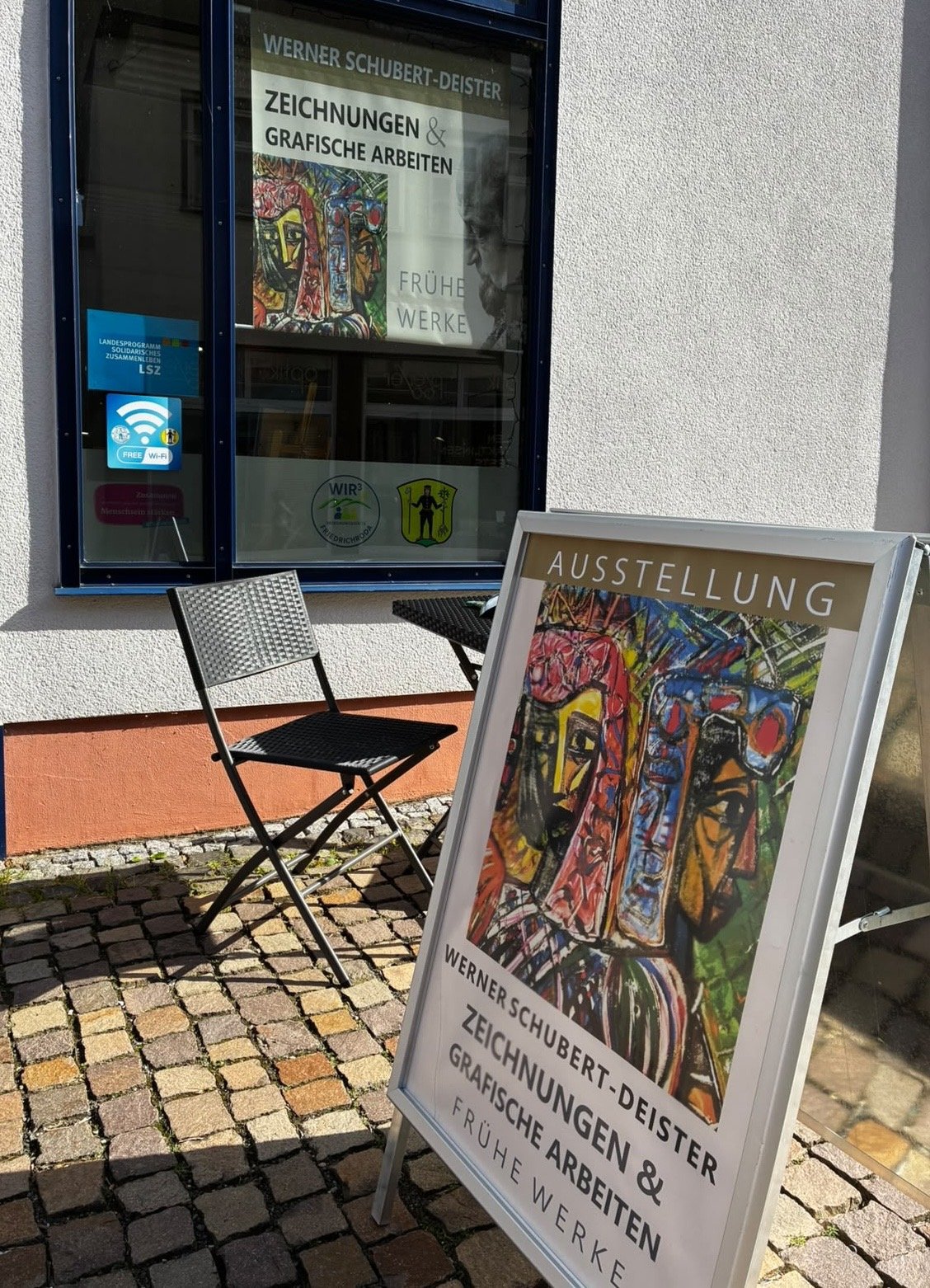 Ausstellungsplakat und Aufsteller vor der Begegnungsstätte WIR³
